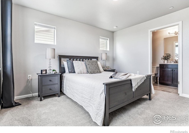 bedroom with baseboards, light carpet, a sink, and ensuite bathroom