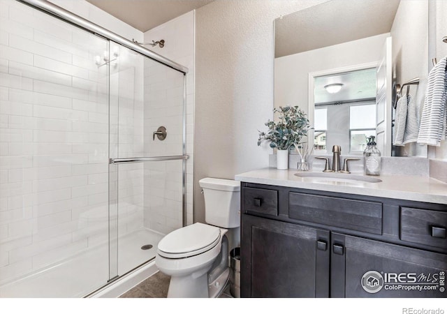 full bathroom with toilet, vanity, tile patterned floors, and a stall shower