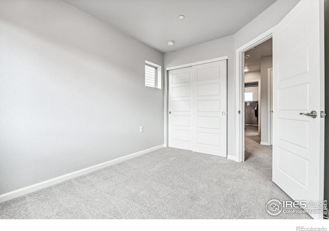 unfurnished bedroom with baseboards, carpet, and a closet