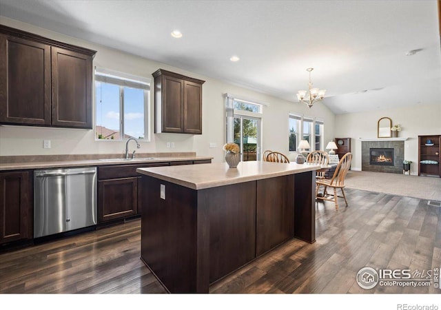 kitchen featuring a tile fireplace, sink, stainless steel dishwasher, dark brown cabinets, and a kitchen island