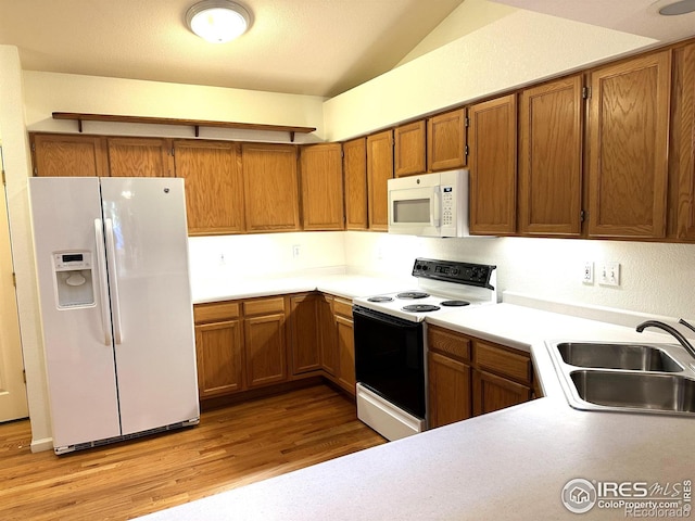 kitchen featuring light wood-type flooring, white appliances, vaulted ceiling, and sink