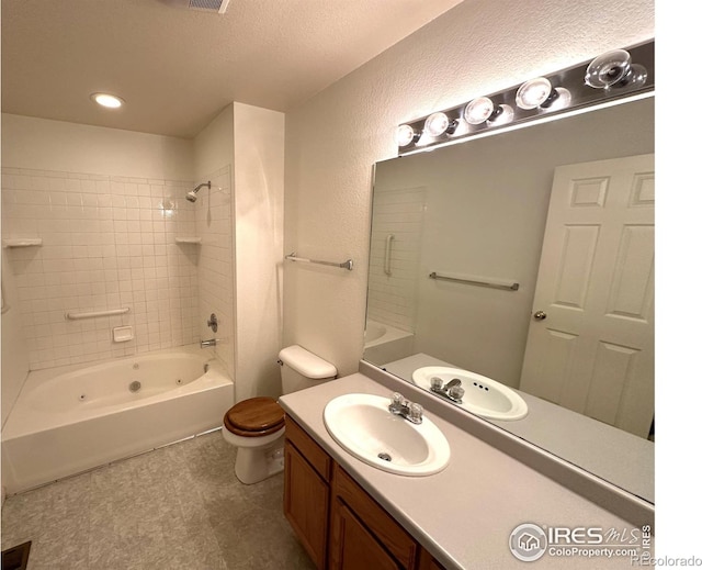 full bathroom featuring a textured ceiling, tiled shower / bath combo, vanity, and toilet