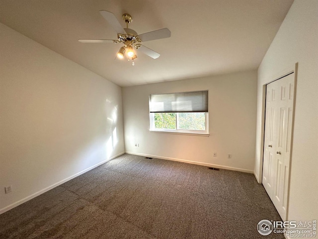 unfurnished bedroom featuring dark carpet, ceiling fan, and a closet