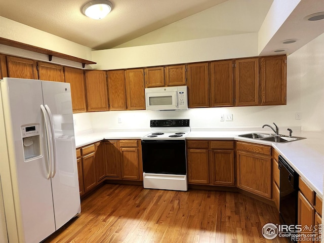 kitchen with white appliances, vaulted ceiling, hardwood / wood-style floors, and sink