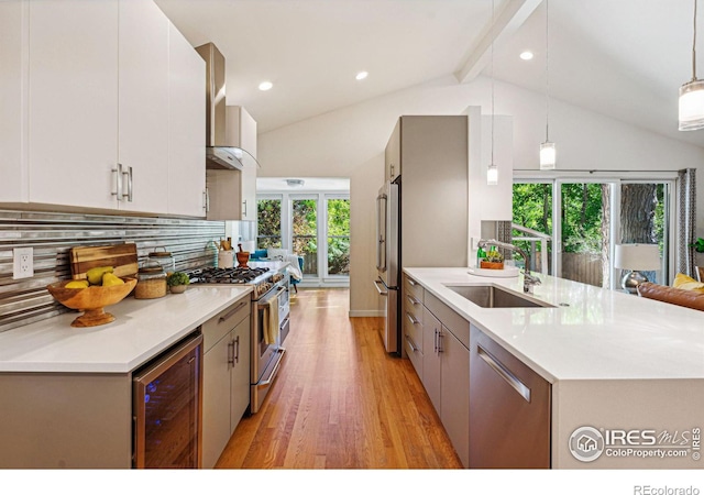 kitchen featuring a healthy amount of sunlight, high end appliances, hanging light fixtures, sink, and wine cooler