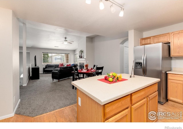 kitchen featuring ceiling fan, light brown cabinets, stainless steel fridge with ice dispenser, a center island, and light wood-type flooring