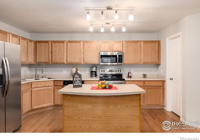 kitchen with pendant lighting, light hardwood / wood-style floors, sink, a kitchen island, and stainless steel appliances