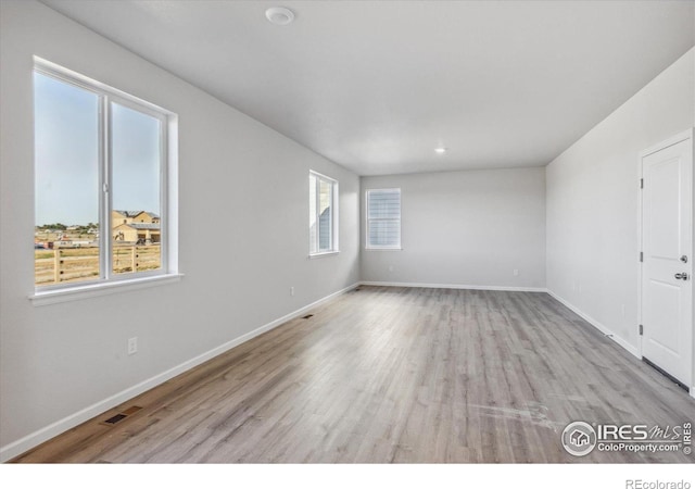 empty room with light hardwood / wood-style flooring and a wealth of natural light