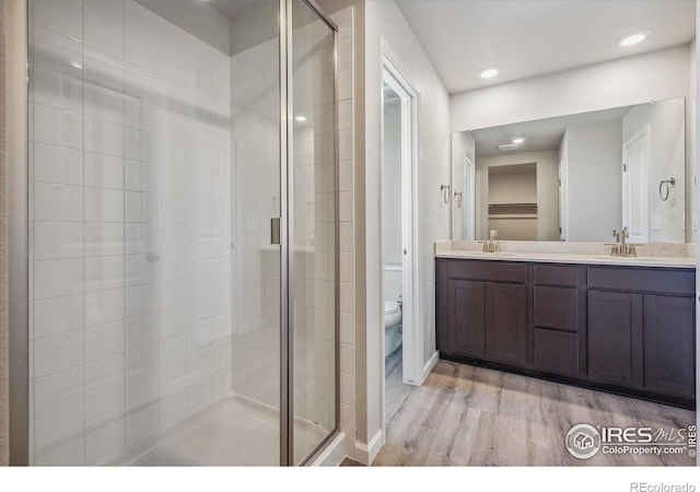 bathroom featuring vanity, a shower with door, hardwood / wood-style floors, and toilet