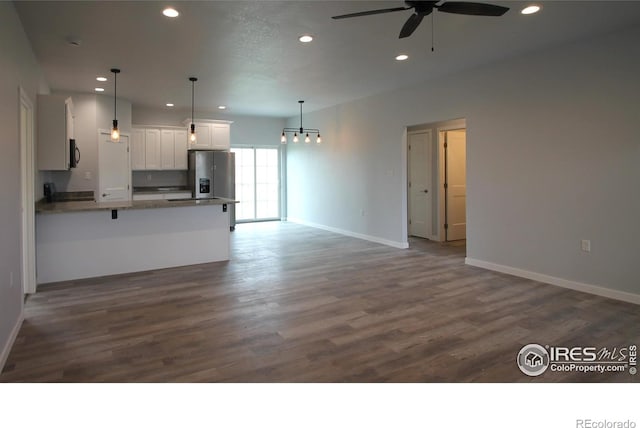 kitchen with appliances with stainless steel finishes, ceiling fan, dark wood-type flooring, pendant lighting, and white cabinetry