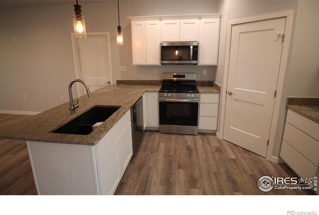 kitchen with appliances with stainless steel finishes, dark hardwood / wood-style flooring, sink, pendant lighting, and white cabinetry