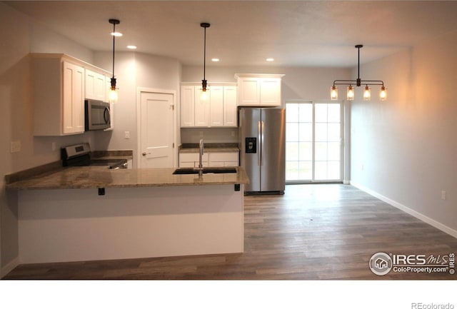 kitchen featuring white cabinets, decorative light fixtures, sink, and appliances with stainless steel finishes