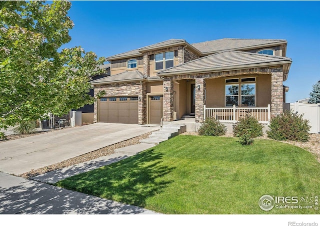 prairie-style house with covered porch, fence, concrete driveway, stucco siding, and a front yard