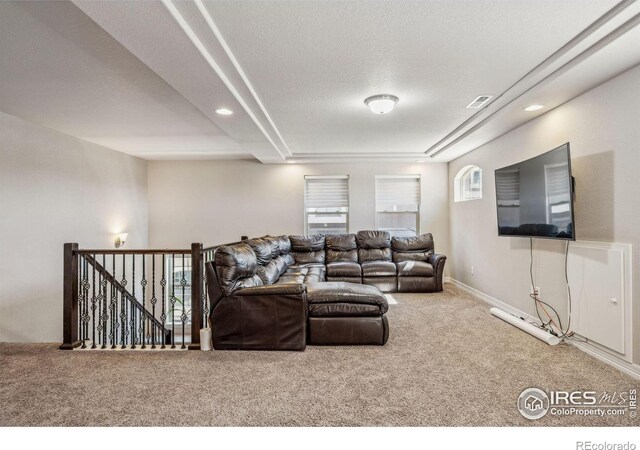 carpeted living area featuring plenty of natural light, a textured ceiling, visible vents, and baseboards