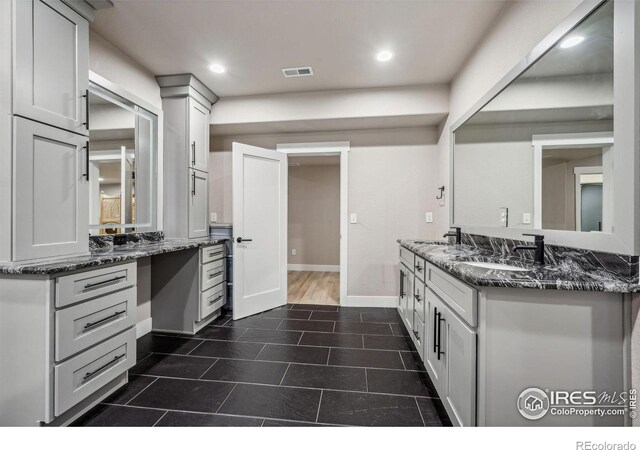 kitchen with recessed lighting, a sink, visible vents, baseboards, and dark stone counters