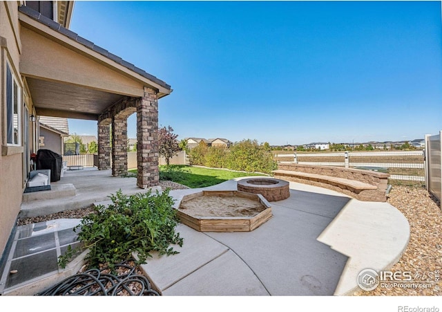 view of patio with fence and a fire pit