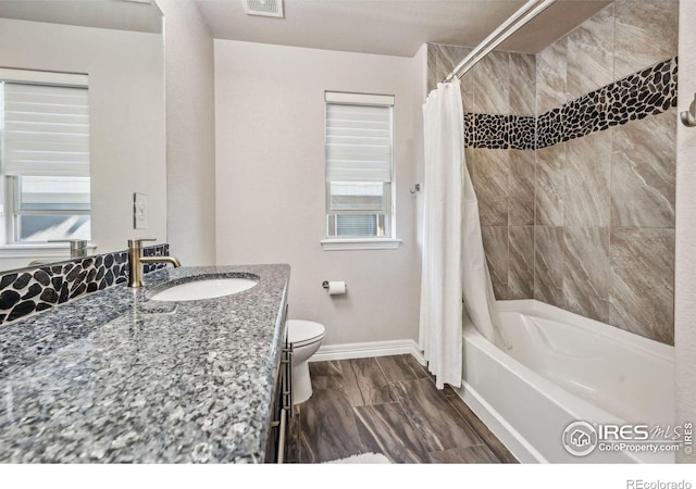 bathroom with a wealth of natural light, toilet, shower / bath combo, vanity, and baseboards