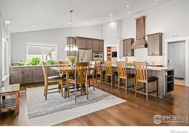 dining area featuring high vaulted ceiling, dark wood-type flooring, and a notable chandelier