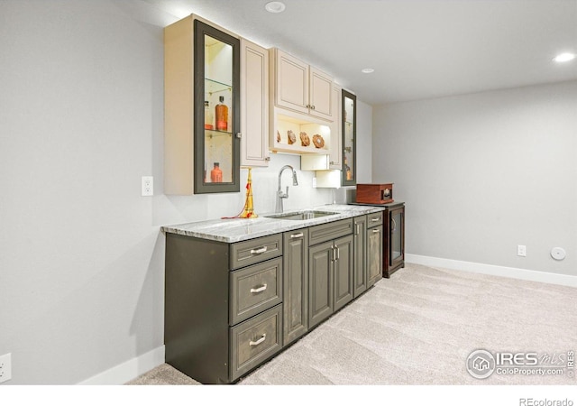 kitchen with gray cabinets, light stone countertops, sink, and light colored carpet