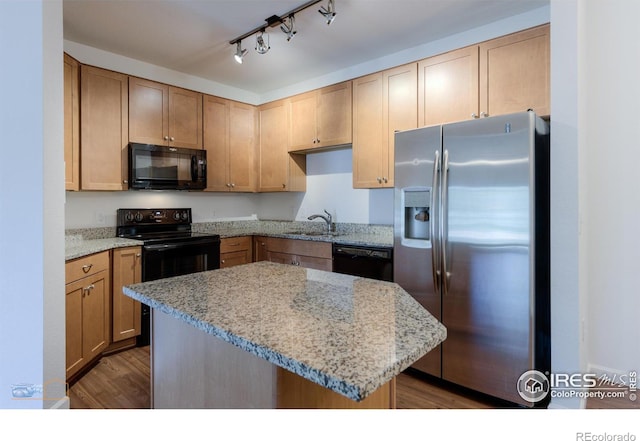 kitchen featuring light stone countertops, black appliances, a center island, dark hardwood / wood-style floors, and sink