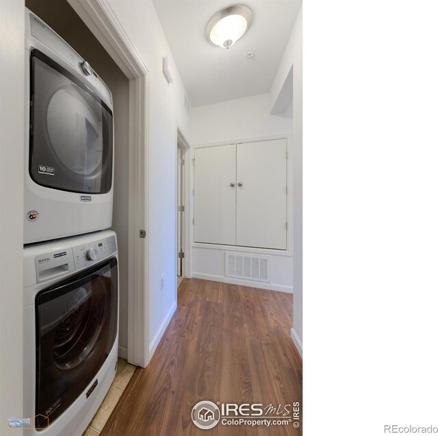 laundry room featuring stacked washer and dryer and hardwood / wood-style floors