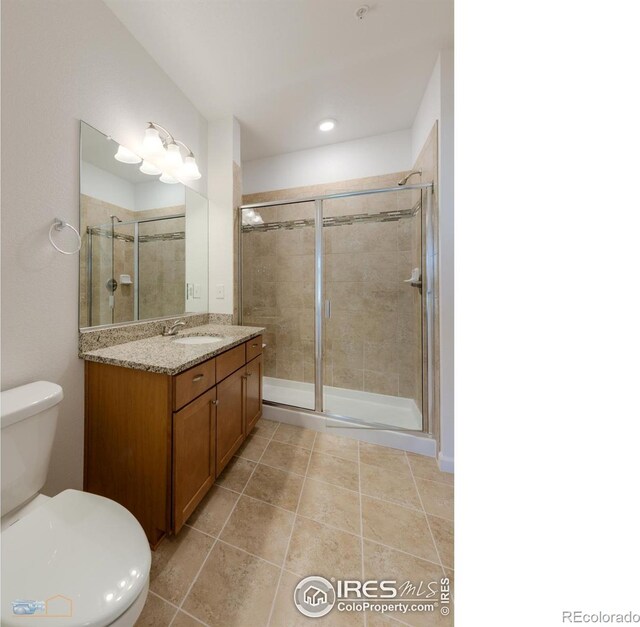 bathroom featuring tile patterned floors, a shower with shower door, vanity, and toilet