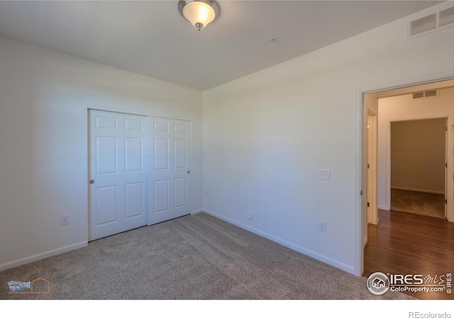 unfurnished bedroom with dark colored carpet and a closet