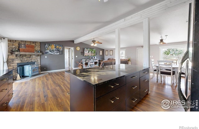 kitchen featuring vaulted ceiling with beams, dark stone counters, open floor plan, and dark wood-type flooring