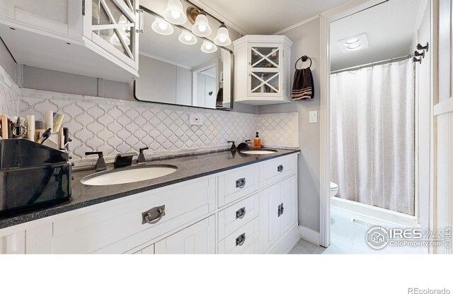 full bathroom featuring double vanity, tasteful backsplash, a sink, and toilet