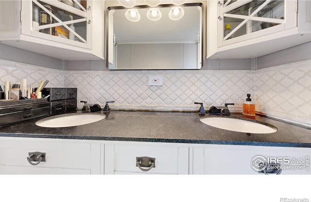 kitchen with dark countertops, a sink, glass insert cabinets, and white cabinetry