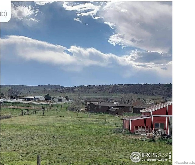 view of yard with an outbuilding, a mountain view, and a rural view