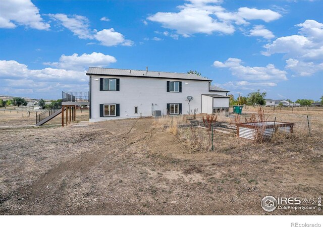 rear view of house with a deck, central air condition unit, and a rural view