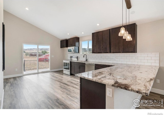 kitchen featuring hanging light fixtures, decorative backsplash, light stone counters, stainless steel appliances, and sink