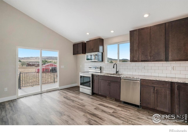 kitchen with stainless steel appliances, vaulted ceiling, light hardwood / wood-style floors, and a healthy amount of sunlight