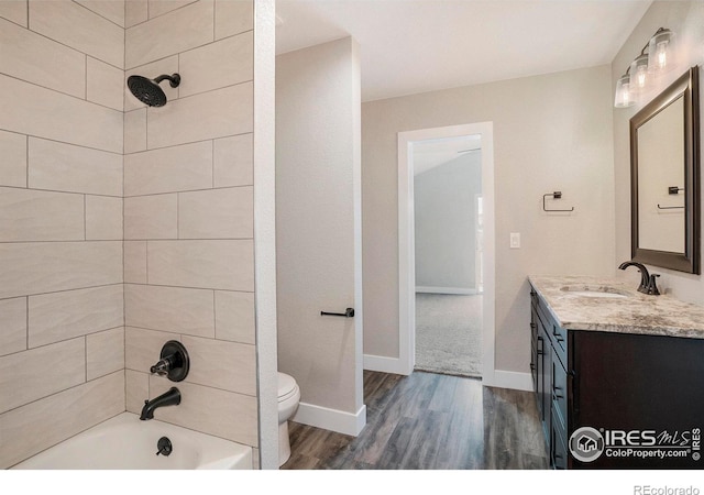 full bathroom with wood-type flooring, tiled shower / bath combo, vanity, and toilet