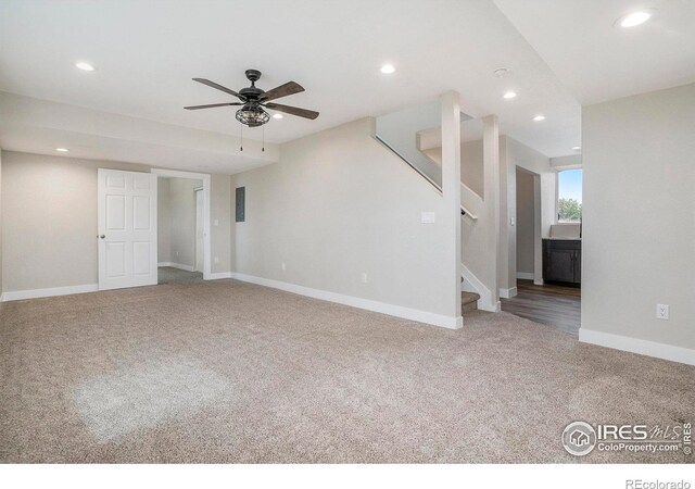 unfurnished living room featuring carpet, electric panel, and ceiling fan