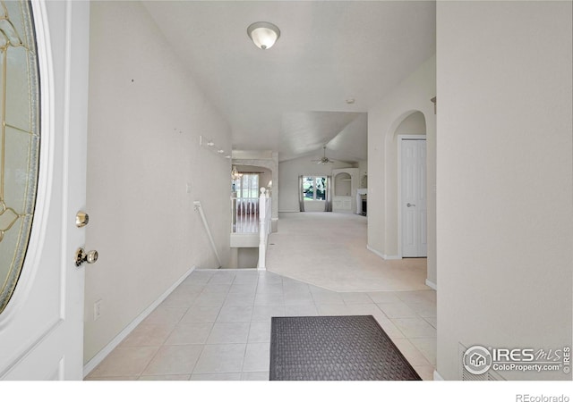 foyer entrance featuring light carpet, vaulted ceiling, and ceiling fan