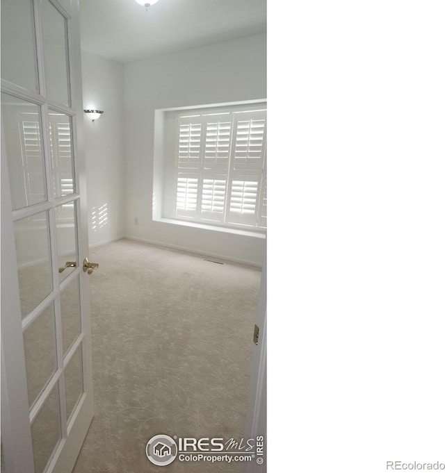 carpeted spare room with french doors