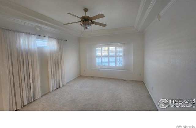 carpeted spare room with crown molding, ceiling fan, and a tray ceiling