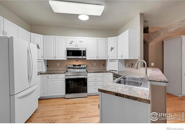 kitchen with sink, appliances with stainless steel finishes, white cabinetry, kitchen peninsula, and light wood-type flooring