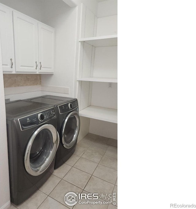 clothes washing area featuring cabinets, washer and dryer, and light tile patterned floors