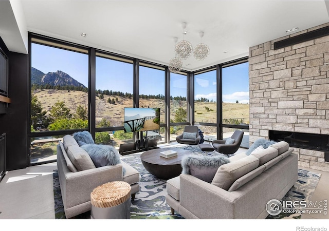 living room featuring a mountain view, a wall of windows, a fireplace, and a chandelier