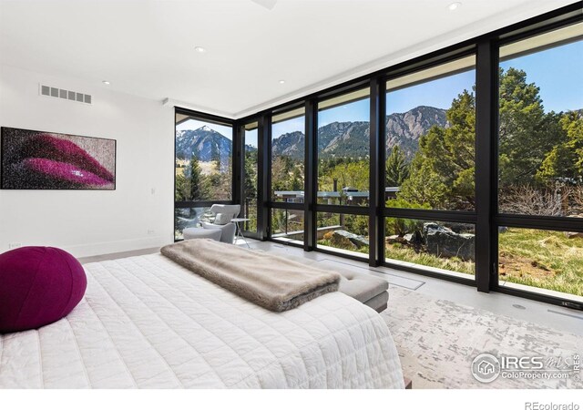 bedroom with floor to ceiling windows and a mountain view