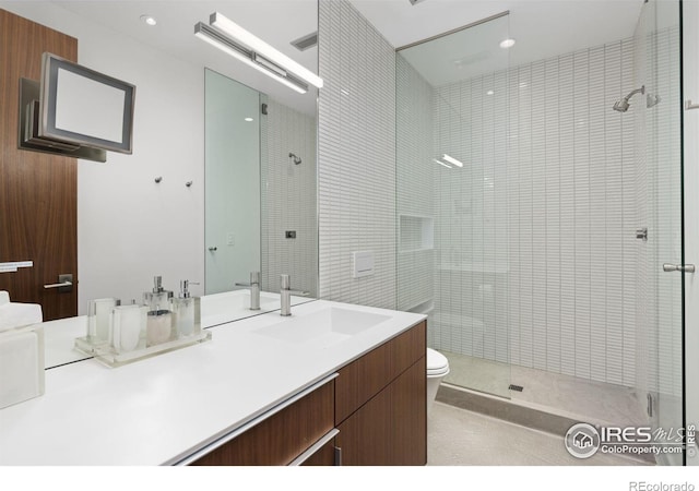 bathroom featuring toilet, vanity, and a shower with shower door