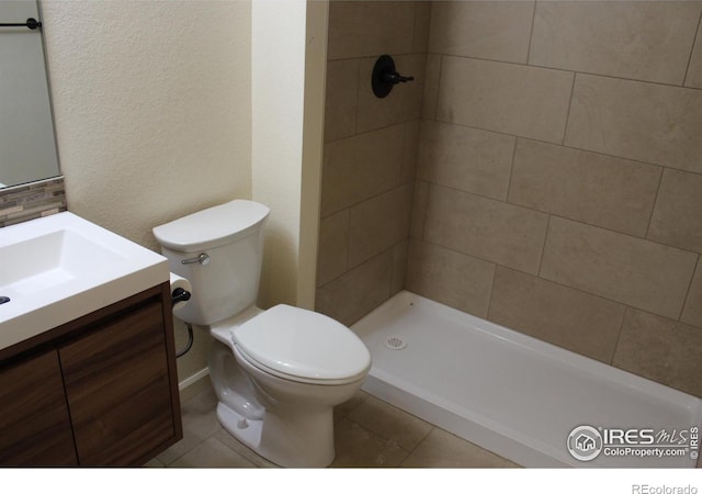 bathroom featuring toilet, vanity, tile patterned floors, and tiled shower