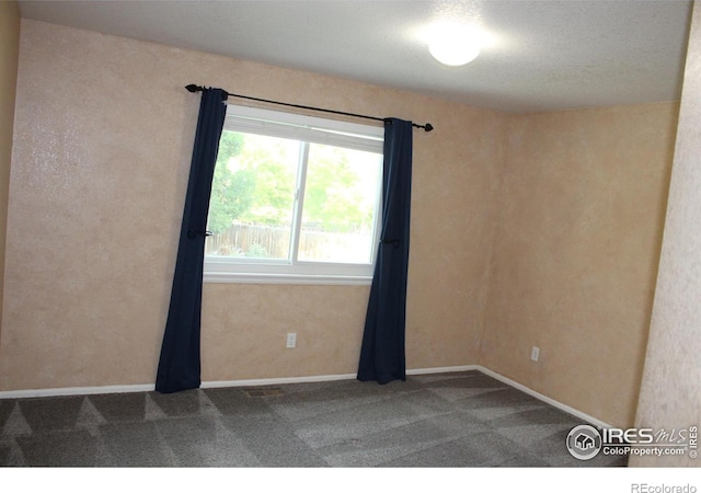 unfurnished room featuring carpet and a textured ceiling