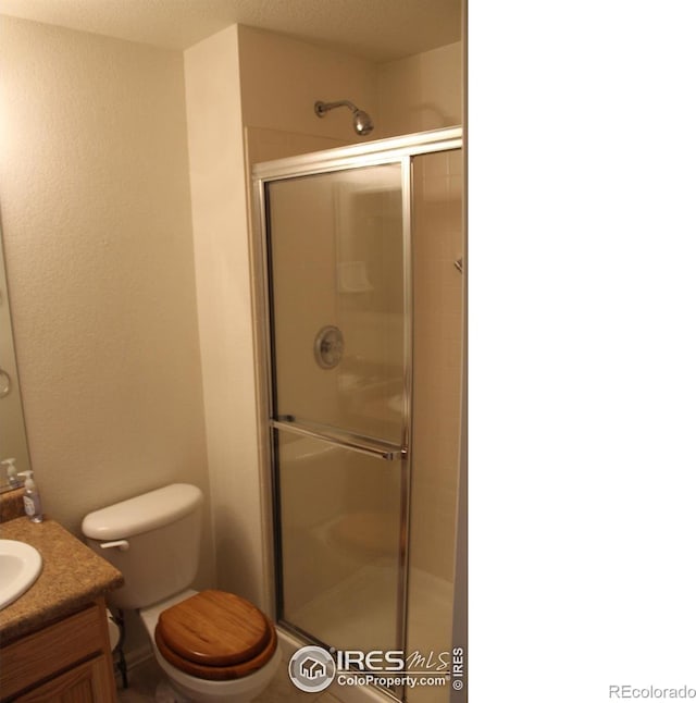 bathroom featuring vanity, a textured ceiling, toilet, and an enclosed shower