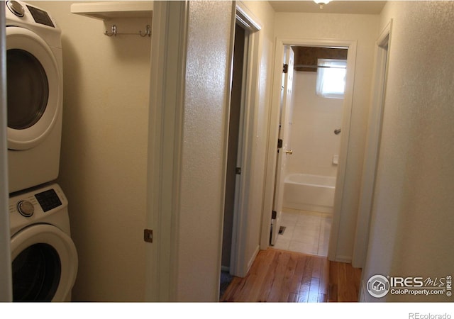 clothes washing area featuring stacked washing maching and dryer and light wood-type flooring