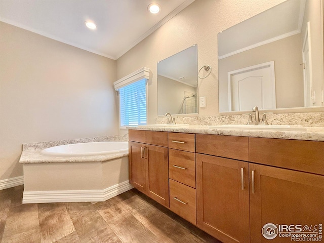 bathroom with vanity, crown molding, hardwood / wood-style floors, and a washtub