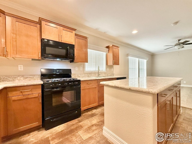 kitchen with ceiling fan, ornamental molding, black appliances, a center island, and a sink